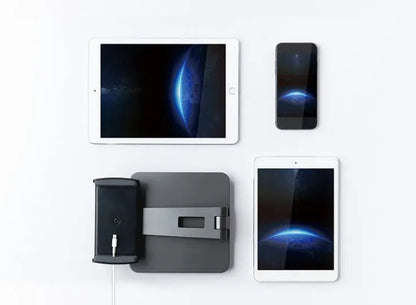 Silver foldable aluminium phone and tablet holder on a wooden desk, showing 360-degree rotation and silicone pads.
