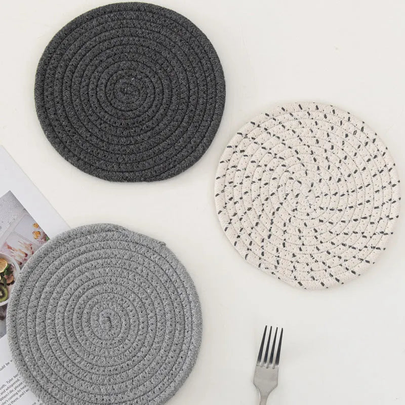 Set of three round grey cotton cord coasters, each 18cm in diameter, on a wooden table.