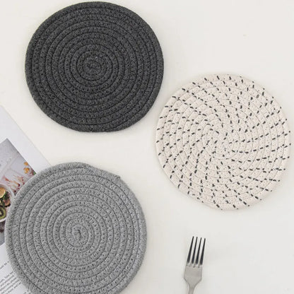 Set of three round grey cotton cord coasters, each 18cm in diameter, on a wooden table.