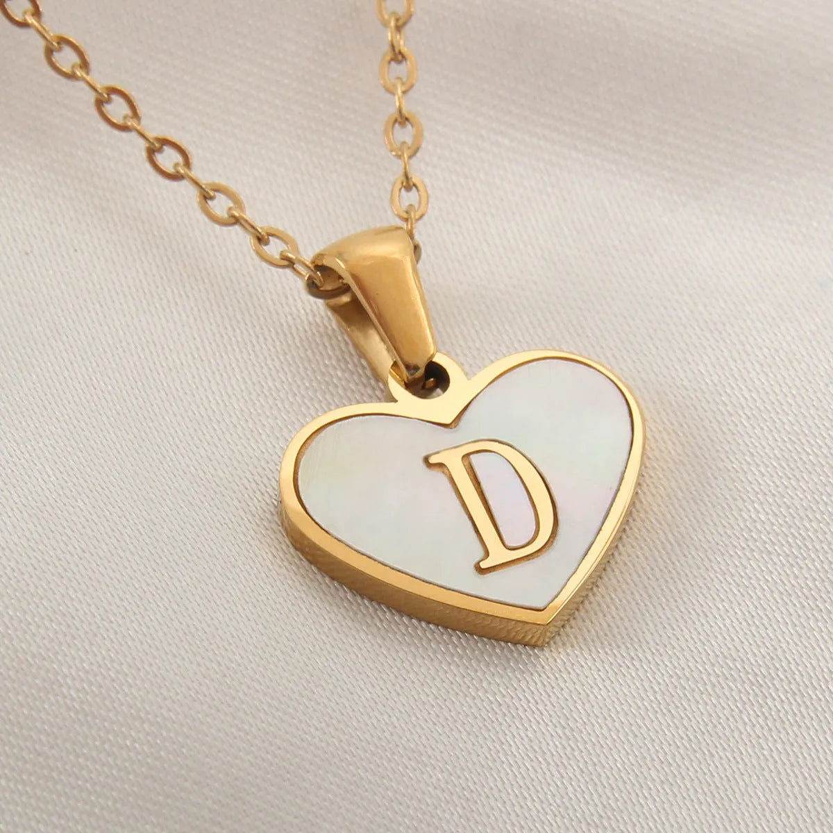 Gold-plated clavicle necklace with a white shell heart pendant, personalised with a letter from A to Z.