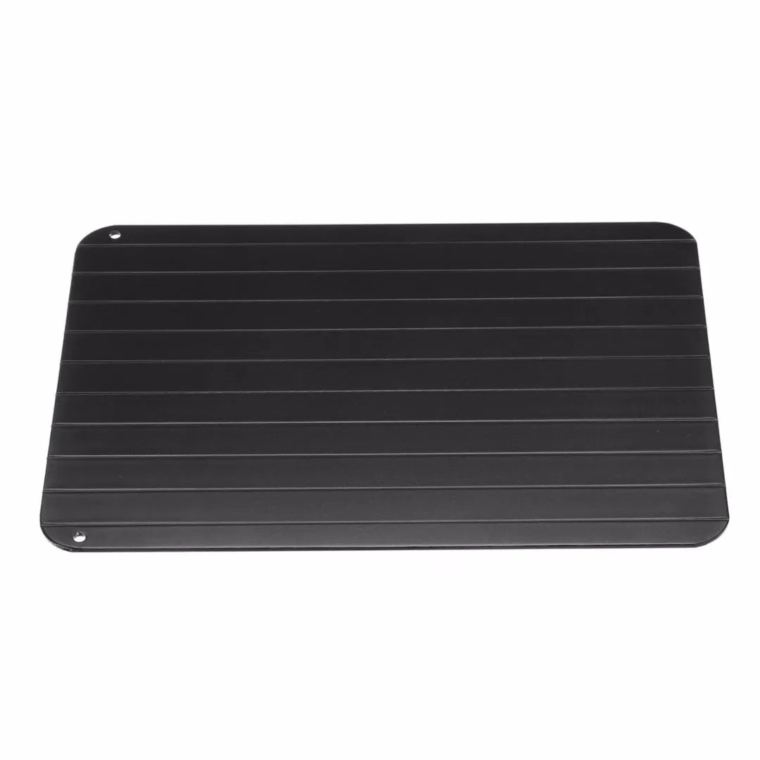 Black aluminium fast defrosting tray for kitchen use, shown thawing frozen meat.