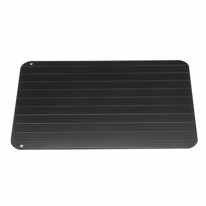 Black aluminium fast defrosting tray for kitchen use, shown thawing frozen meat.