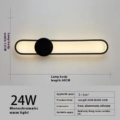 Round black iron wall sconce with integrated LED light glowing on a modern grey wall
