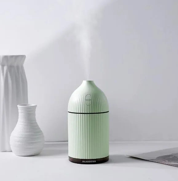 White USB-powered ultrasonic aromatherapy diffuser and humidifier with 300ml bottle and LED light on a desk.