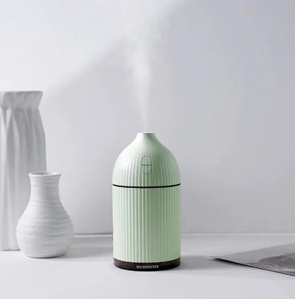White USB-powered ultrasonic aromatherapy diffuser and humidifier with 300ml bottle and LED light on a desk.
