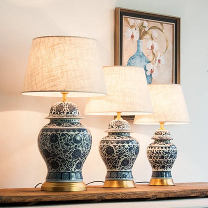 Traditional blue and white Chinese ceramic table lamp with a cloth shade on a bedside table.