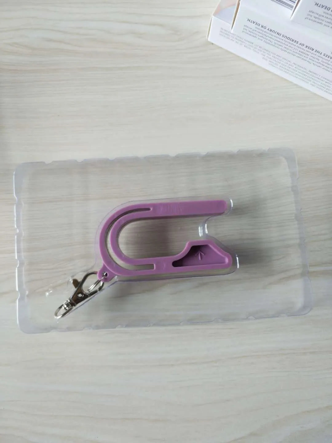 Plastic car seat key for child car seat red button, shown in Pink, Violet, or green, stored on a keychain.