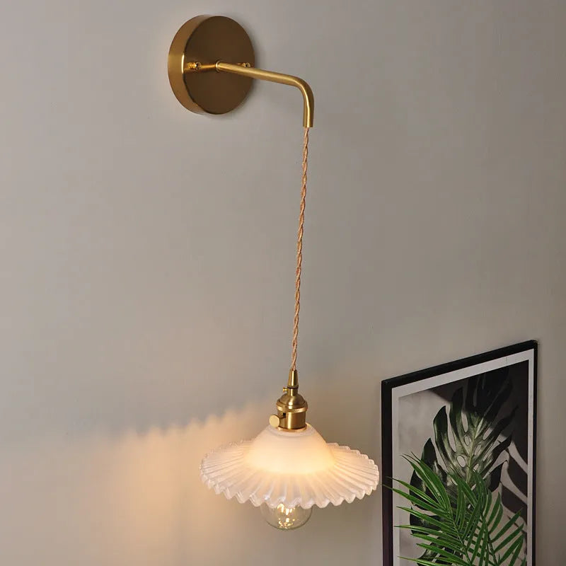 Retro brass lotus wall lamp with copper body and glass shade in various colours, mounted on a wall