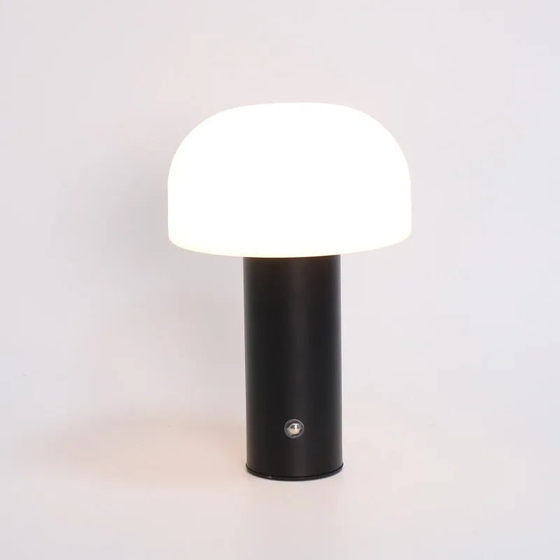 Compact white USB table lamp with integrated UK plug and a charging cable on a wooden desk.