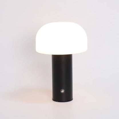 Compact white USB table lamp with integrated UK plug and a charging cable on a wooden desk.