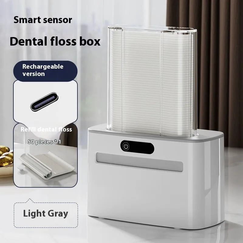 Dark grey automatic electric dental floss box with pop-up mechanism on a bathroom counter.