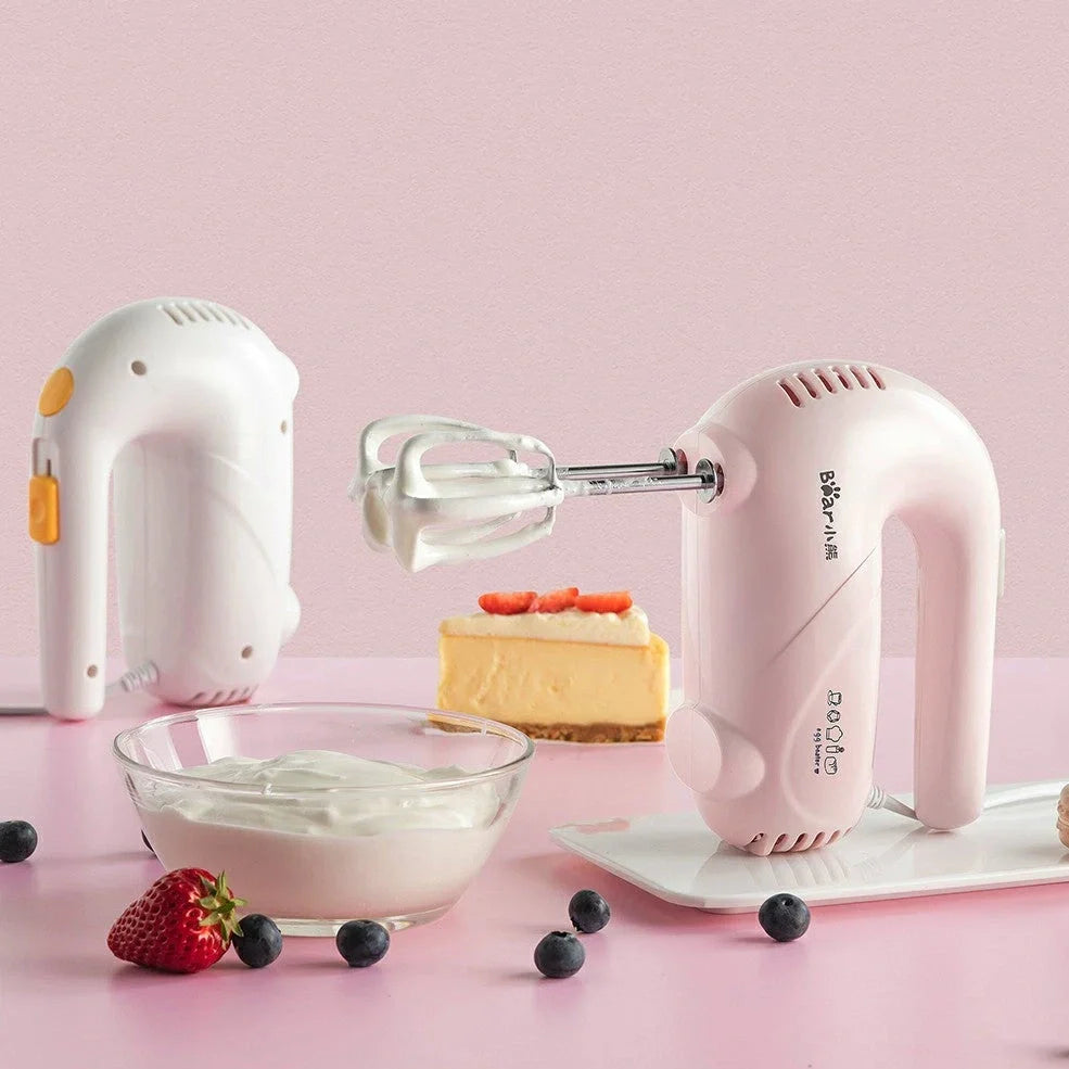 Pink electric hand whisk with stainless steel attachments for whipping eggs and cream