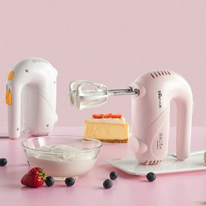 Pink electric hand whisk with stainless steel attachments for whipping eggs and cream