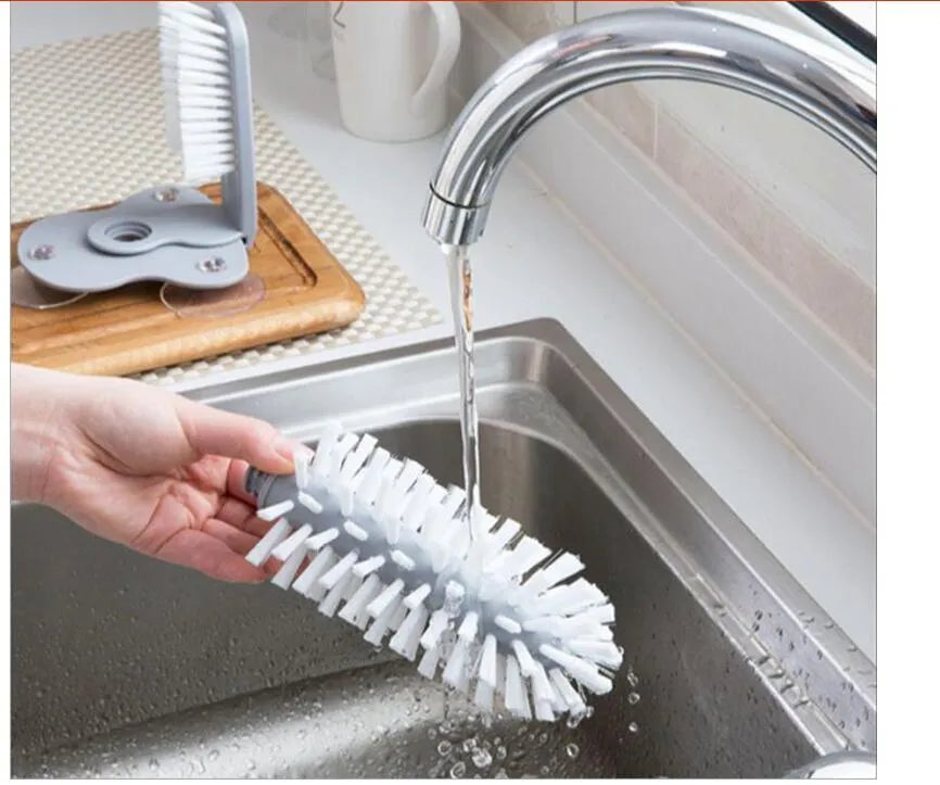 Grey rotating double-head cup brush with suction cups for wall mounting.