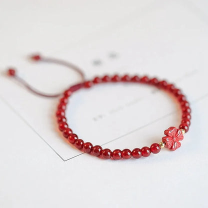 Hand-woven red agate beads bracelet with lucky charm in ethnic style, showing diamond-shaped beads.