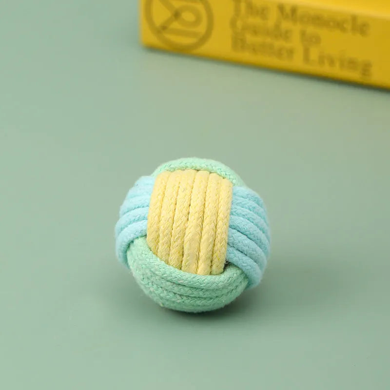 Handmade blue and green cotton plush ball cat toy, 5cm in diameter, on a wooden floor.