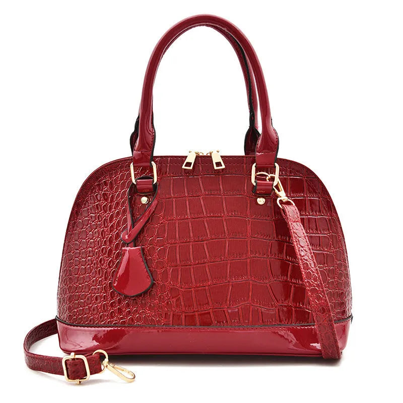 Shiny black PU leather crossbody bag with a structured shell shape and a long strap.