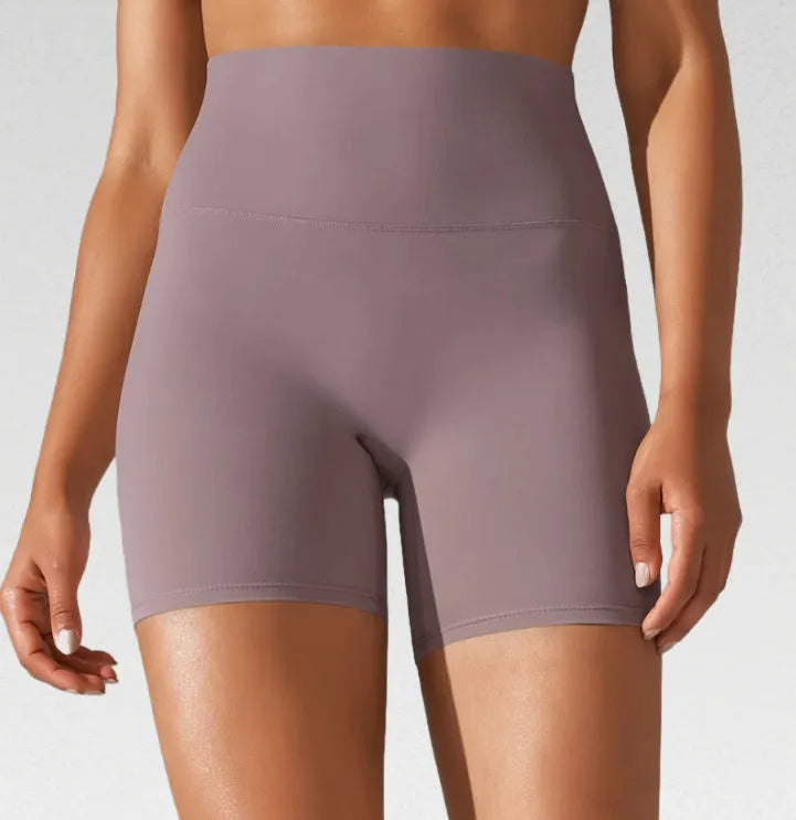 Woman wearing high waist hip lift fitness tights in a neutral colour, suitable for running or gym workout.