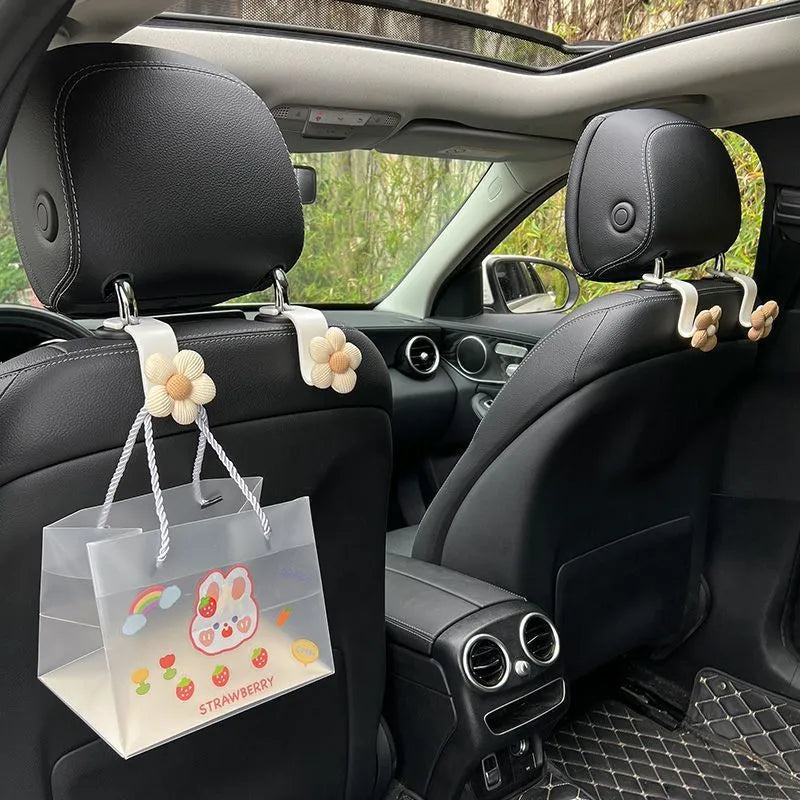 Khaki coloured plastic car seat hook with floral pattern for storage, shown at 11 by 5.5 cm.
