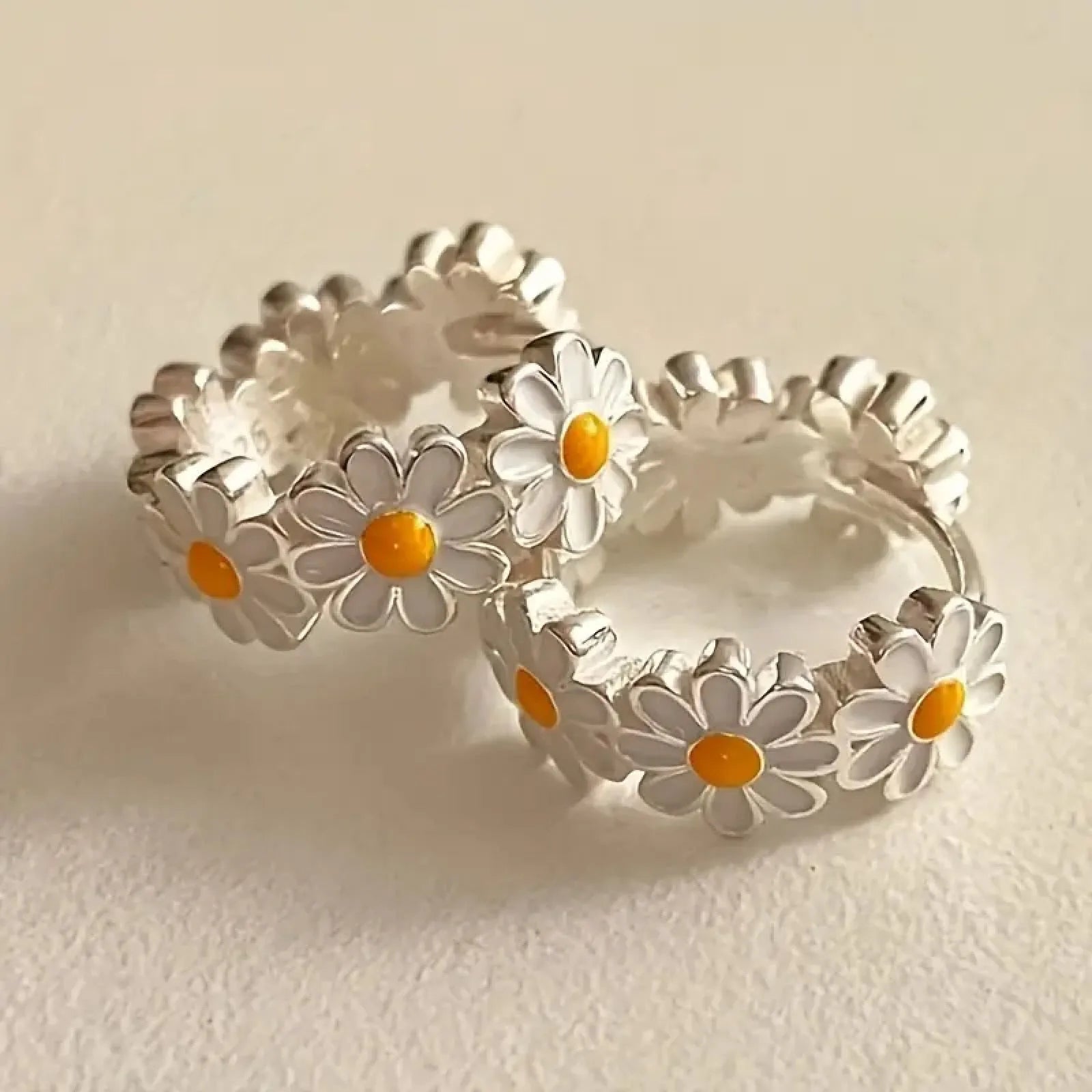 A pair of white daisy flower ring earrings with an inlaid gemstone in a platinum setting.