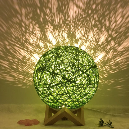 Spherical hand-knitted rattan table lamp with remote control on a wooden desk