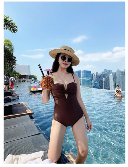 Women's solid colour one-piece swimsuit with spaghetti straps and push-up padding in white, pink, or brown options