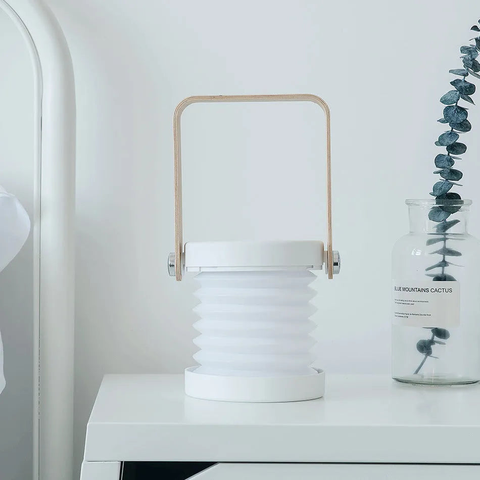 White foldable USB rechargeable LED night light in both table lamp and tall lantern modes.