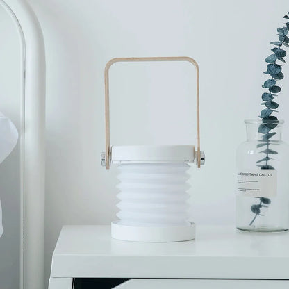 White foldable USB rechargeable LED night light in both table lamp and tall lantern modes.