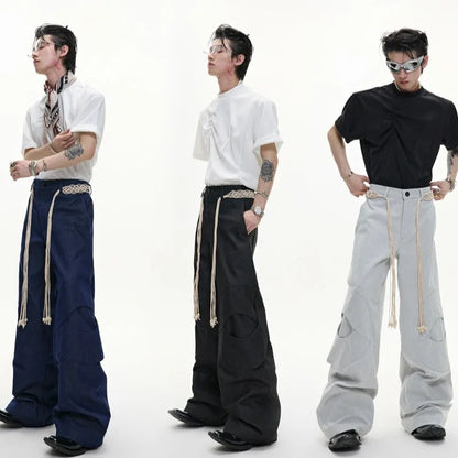 Men's dark blue straight-leg cotton jeans with 3D cutting, belt stitching, and decorative tassel on a hanger
