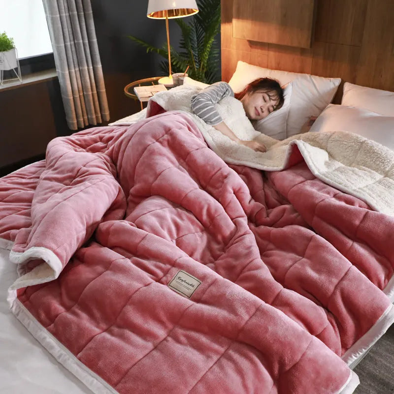 Thick pink coral fleece blanket folded on a twin bed.