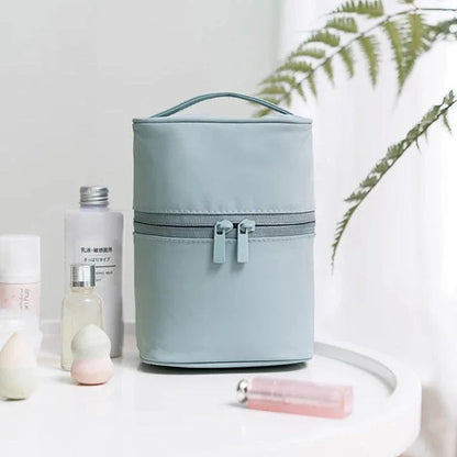 A cylindrical nylon makeup storage bag in a green color, designed for portable and organized beauty on the go.