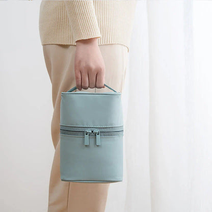 A cylindrical nylon makeup storage bag in a green color, designed for portable and organized beauty on the go.