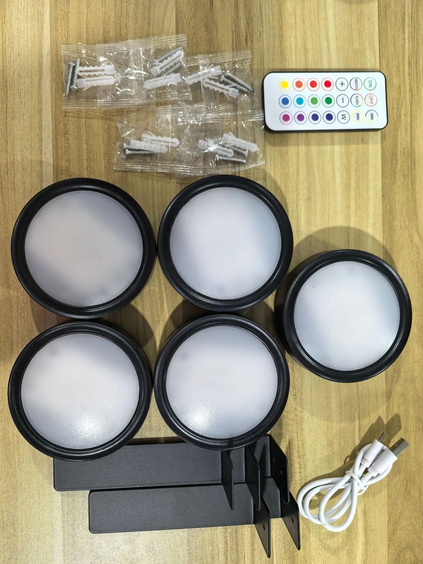 Black magnetic LED painting lamp with remote control on a white wall.
