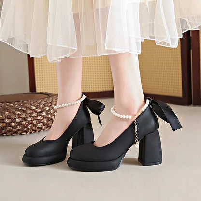 Women's beige Mary Jane shoes with chunky heel, ankle strap, pearl buckle, and round toe on a rubber sole.