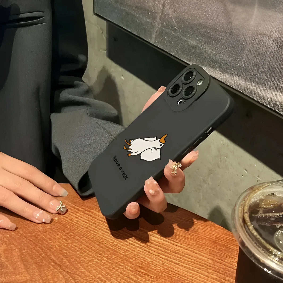 Black silicone iPhone case with a raised carved cartoon duck design on the back.