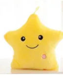 Colourful glowing five-pointed star plush pillow on a dark background.