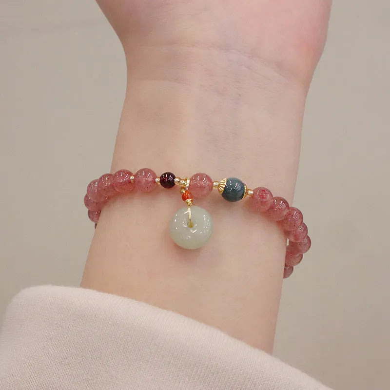 Women's strawberry quartz bracelet with geometric design and decorative purse charm on safety buckle closure