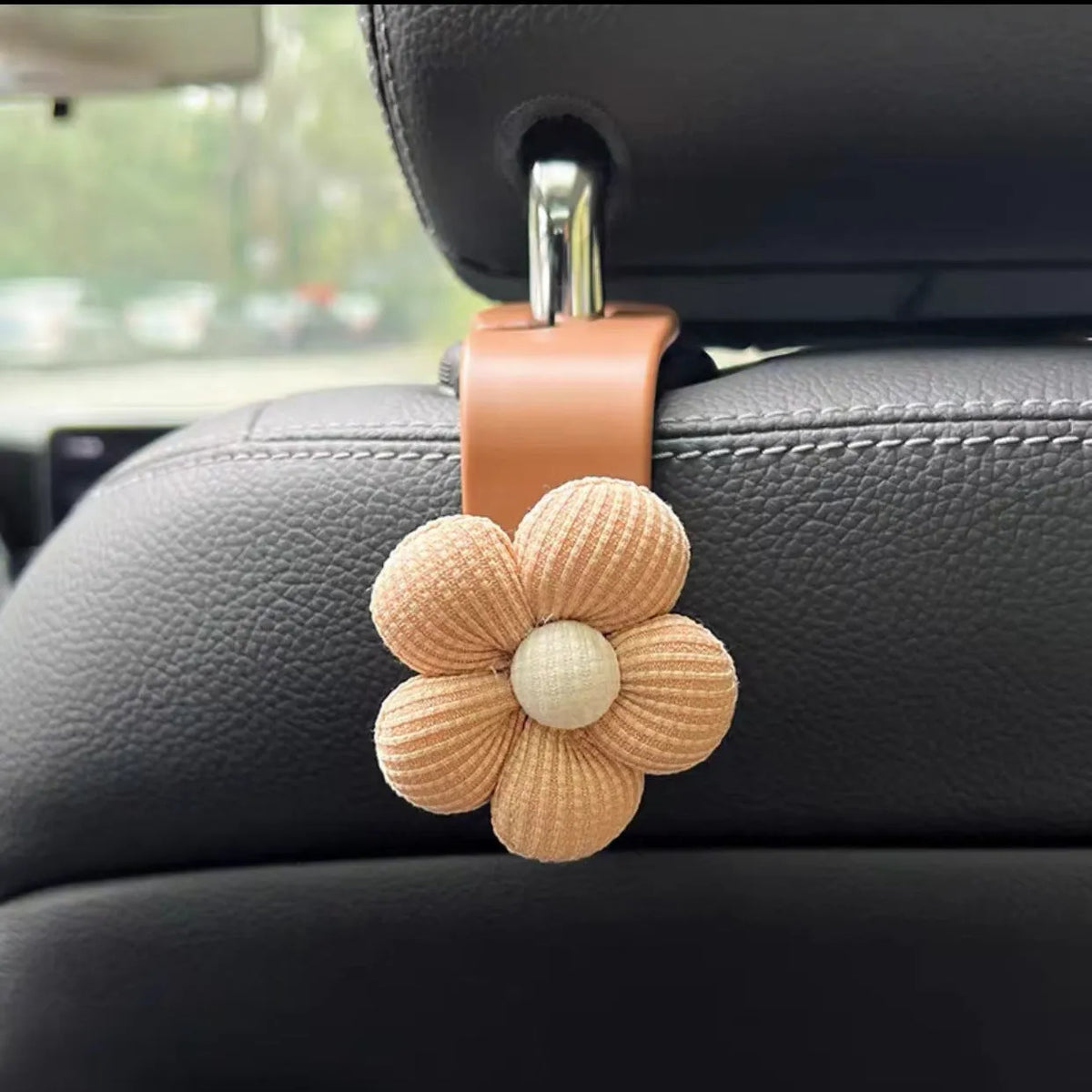 Khaki coloured plastic car seat hook with floral pattern for storage, shown at 11 by 5.5 cm.