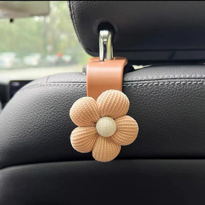 Khaki coloured plastic car seat hook with floral pattern for storage, shown at 11 by 5.5 cm.