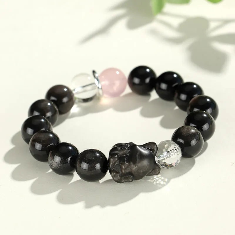 Silver stone crystal bracelet with diamond-shaped fox, cat head, and planet charms on white background.