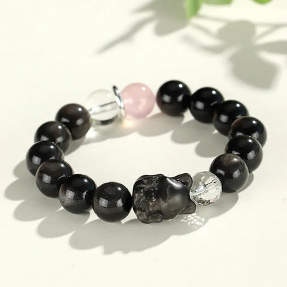 Silver stone crystal bracelet with diamond-shaped fox, cat head, and planet charms on white background.