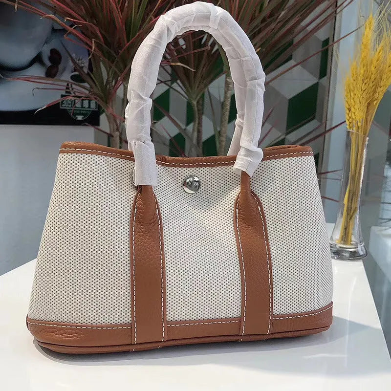 Genuine leather and canvas women's tote bucket bag in black, shown with a soft carry handle.