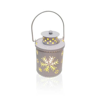 Green wrought iron electronic candle lantern with flickering LED light on a wooden mantel.