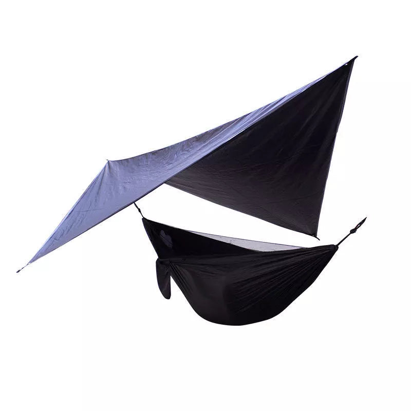 Portable camping hammock with mosquito net and awning setup in a forest