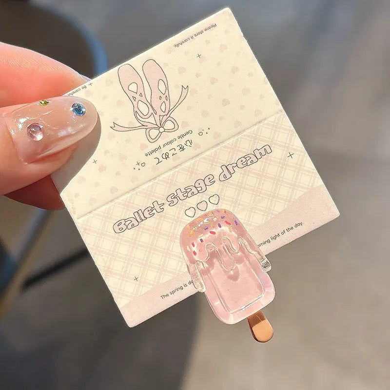 A resin hair barrette with a cartoon ice cream charm on a side-clip, shown in a pink colour variant.