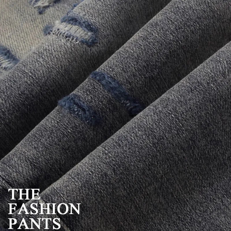 Men's slim fit blue jeans with washed-out finish, hole patches, and embroidery detail.