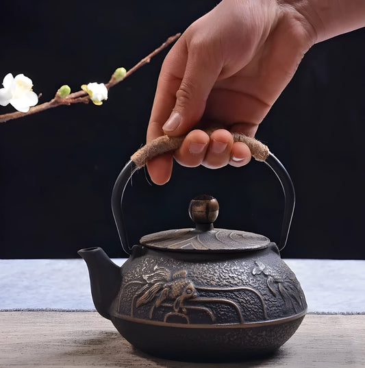 Japanese-style cast iron teapot with lid on a hob, shown in a bronze finish.