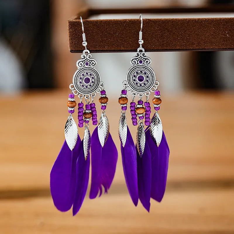 Bohemian feather leaf pattern alloy earrings in round drop shape on a colour selection background.