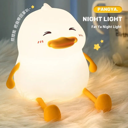 Chubby Night Light with soft glow on bedside table, holding a mobile phone in its silicone cradle.