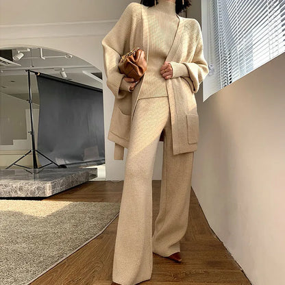 Women's knitted three-piece set with wide-leg trousers, cardigan, and top in solid colours, showing leather stitching details